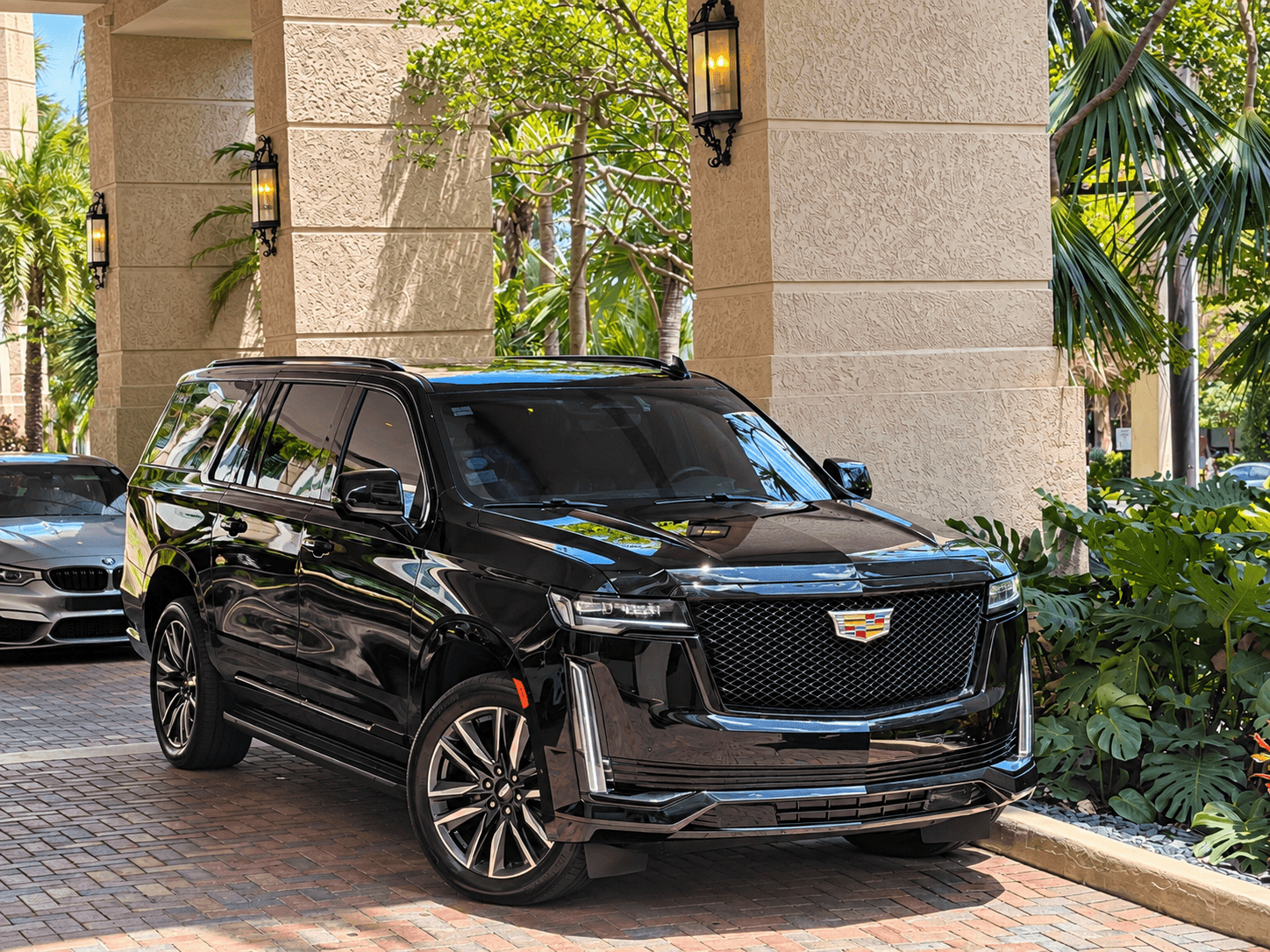 Chauffeur holding the rear door of a luxury SUV open for a passenger